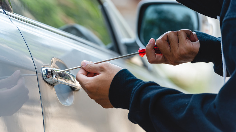 Car thief using a screwdriver to break into a vehicle