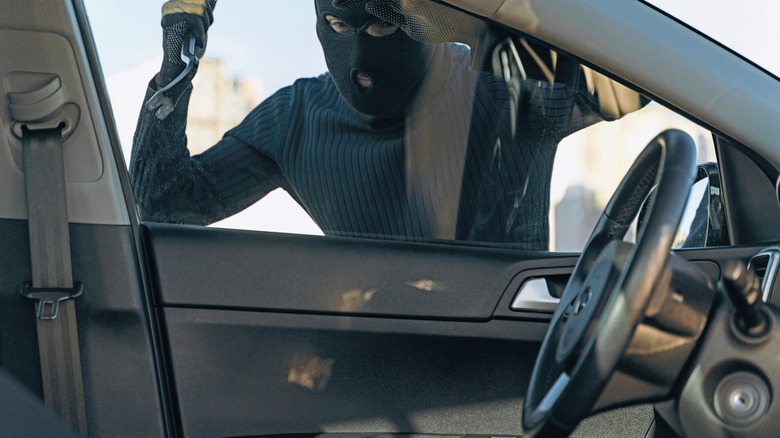 Close up shot of a car thief attempting to break into a vehicle with jemmy