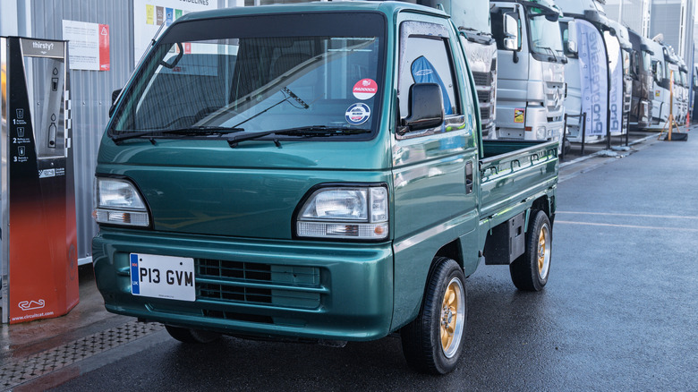 a dark green 1990s Honda Acty truck parked in a truck parking lot