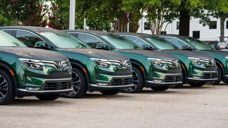 A line of dark green VinFast VF8s