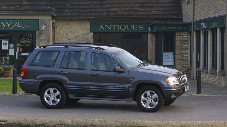 A side view of an old Grand Cherokee parked in front of an antique shop