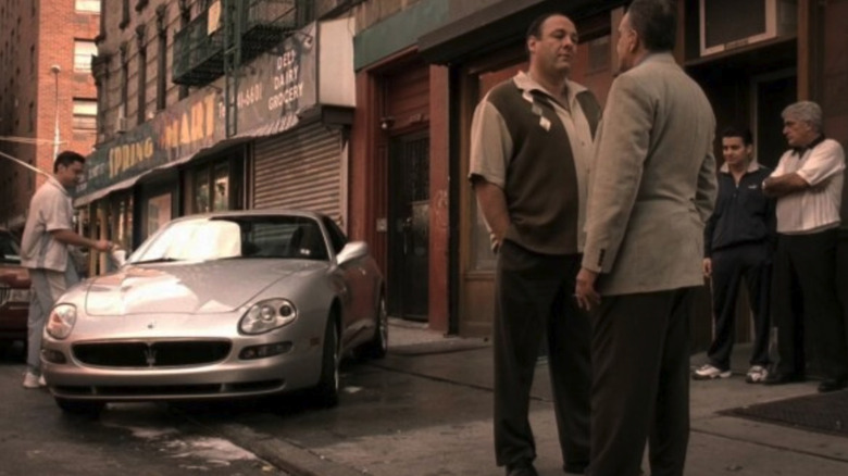 Screenshot of Tony Soprano talking to one of his guys on the street with Christopher's Maseratis getting washed behind them.