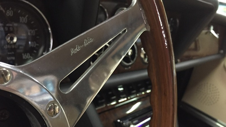 A close-up of a "Moto-Lita"-etched (and made) steering wheel, metal insert with wooden rim,  in an old Jaguar.