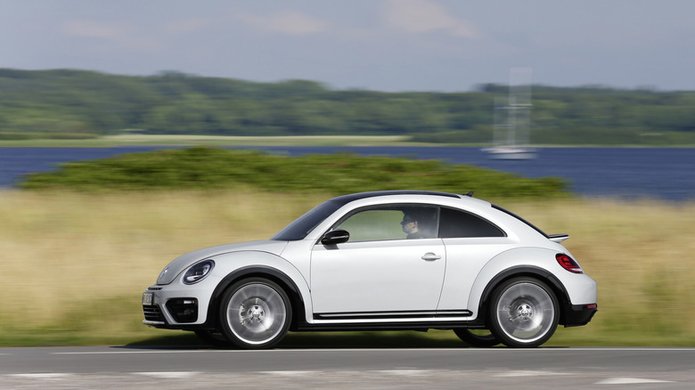 A achromatic Volkswagen Beetle drives from framework correct to framework left