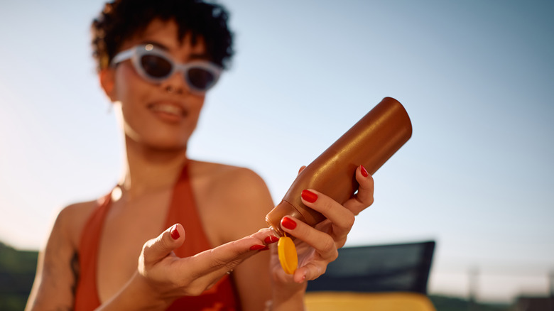 A Black woman applies sunscreen