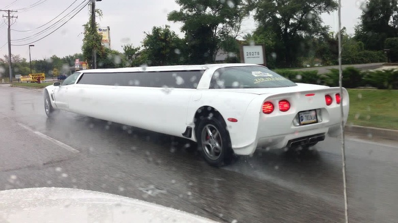 A white Corvette C5 limo driving down a wet road in the rain