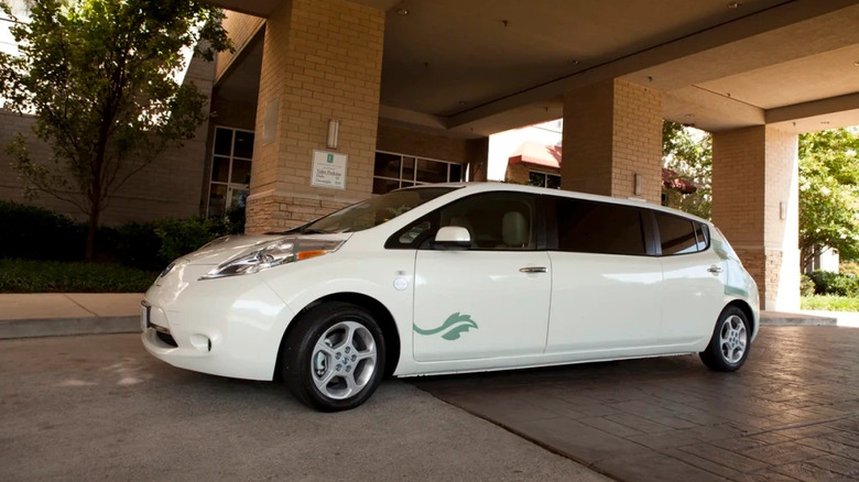 A cursed white Nissan Leaf limo with a green decal on the the driver's door