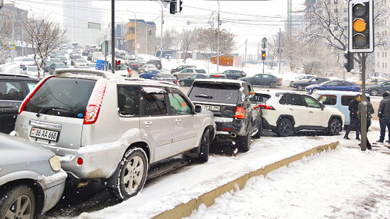 Multi-vehicle car accident and mass collision involving several SUVs on a snowy and slippery city road during a heavy winter blizzard and snowfall in the city