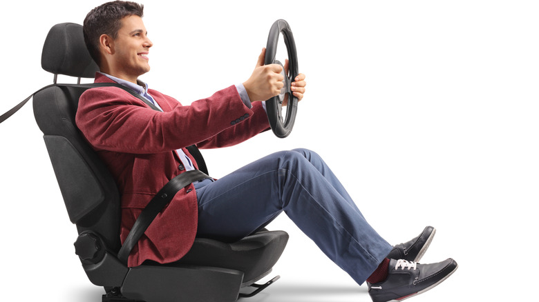 Elegantly dressed guy sitting in a car seat and driving isolated on white background