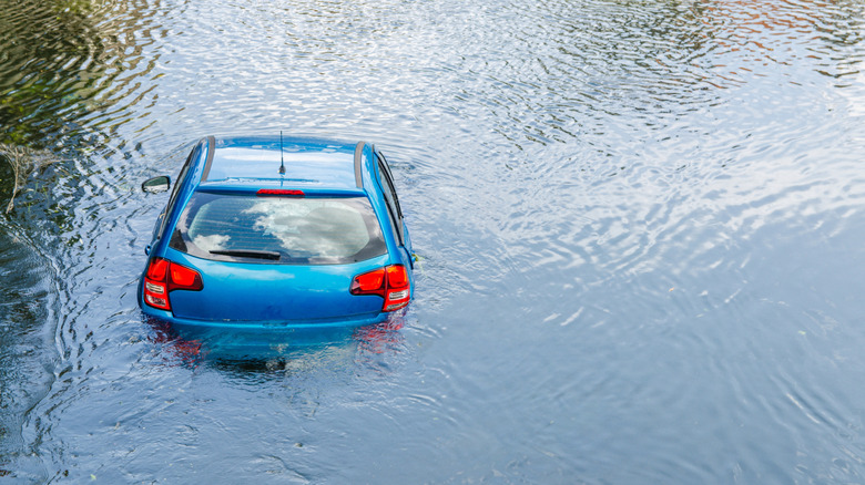 Blue car drown in water canal. Extreme accident vehicle sink in river pound lake, traffic incident