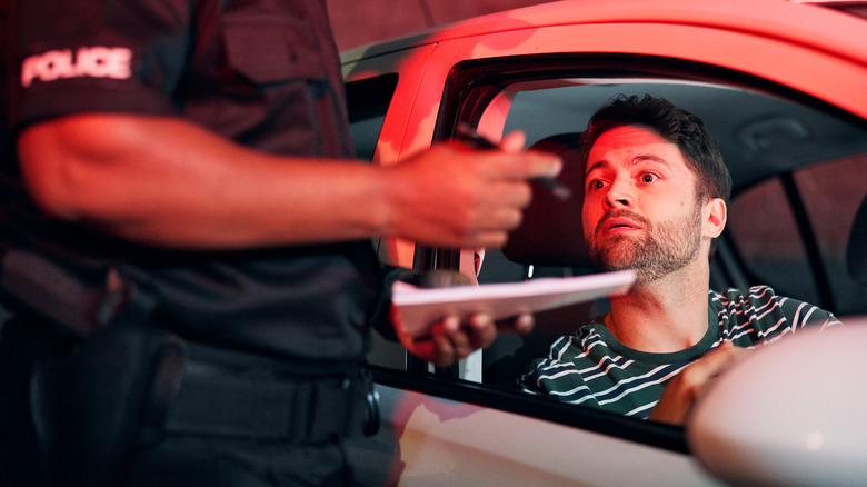 Man sitting in his car with his window down talking to an officer