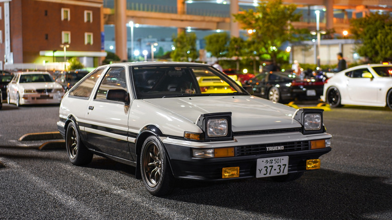 A white Toyota AE86 parked in a parking lot in Japan