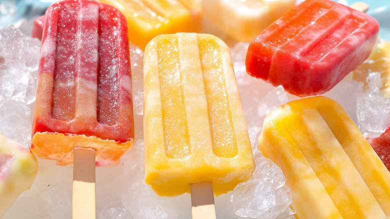 Colorful popsicles on ice cubes with summer lighting.