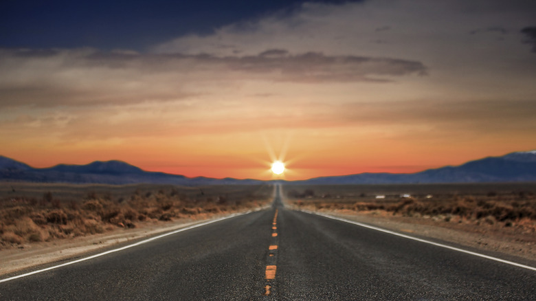 Highway 50 in Nevada, known as the Loneliest Road, displaying a gorgeous sunset across the road.