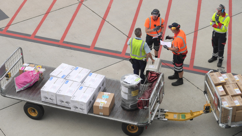 baggage handlers discussing something while standing near packages