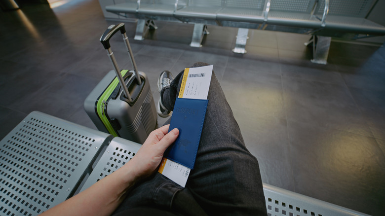 A hand holding a plane ticket in their passport