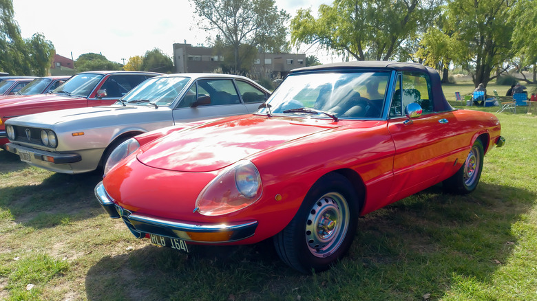 CHASCOMUS, ARGENTINA - Apr 10, 2022: Red sport Alfa Romeo Spider Veloce roadster Series 2 Coda Tronca 1970s on the grass Nature trees in the background Classic car show Copyspace