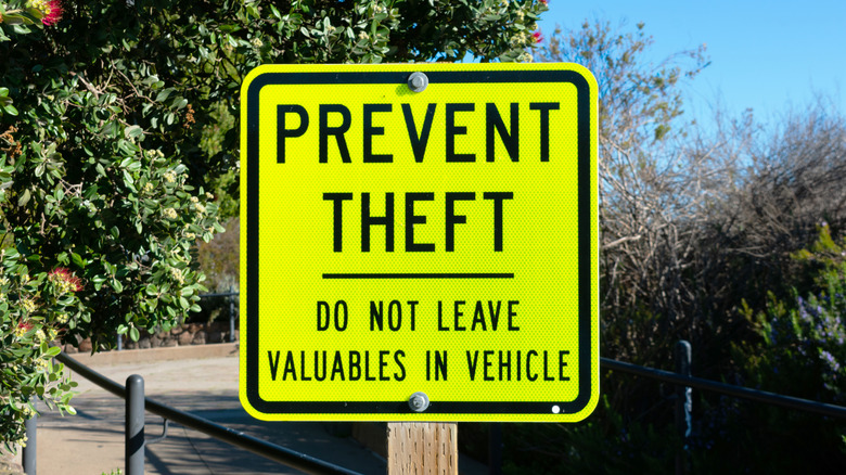 Yellow metal prevent theft sign on wooden post.