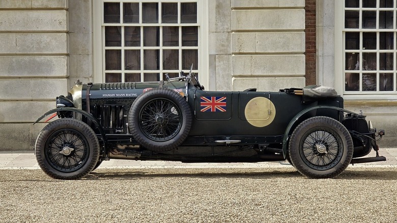A green open-top Bentley Blower in front of an old English estate.