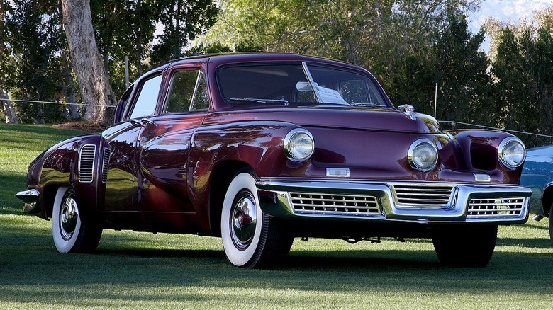 A maroon Tucker 48 known as the Tucker Torpedo on a green lawn for a car show.