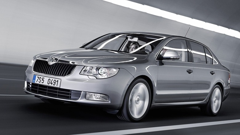 A silver Skoda Superb runs through a lit tunnel — the light reflecting on the shiny surface of the car.