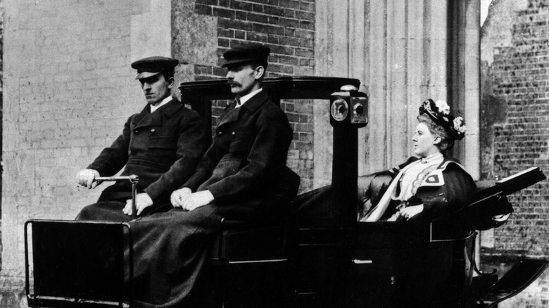 a black-and-white picture of a woman riding in the back of an electric car