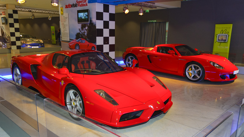 Bright red cars, one ferrari and porsche, parked side by side