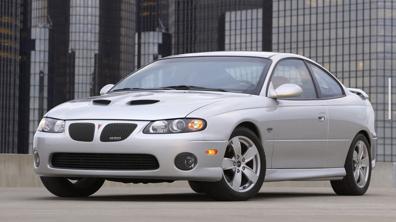 A silver Pontiac GTO parked in front of an office building