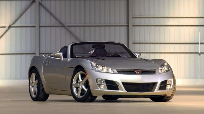 A silver Saturn Sky. convertible parked inside of a barn