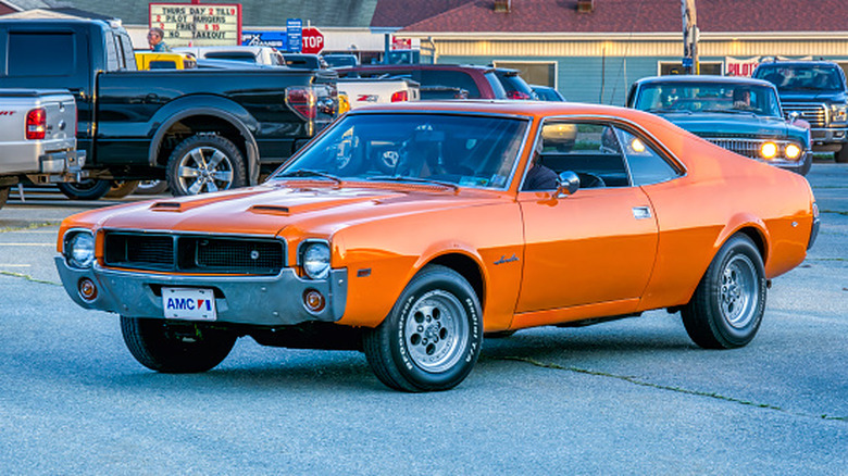an orange amc javelin in a busy parking lot