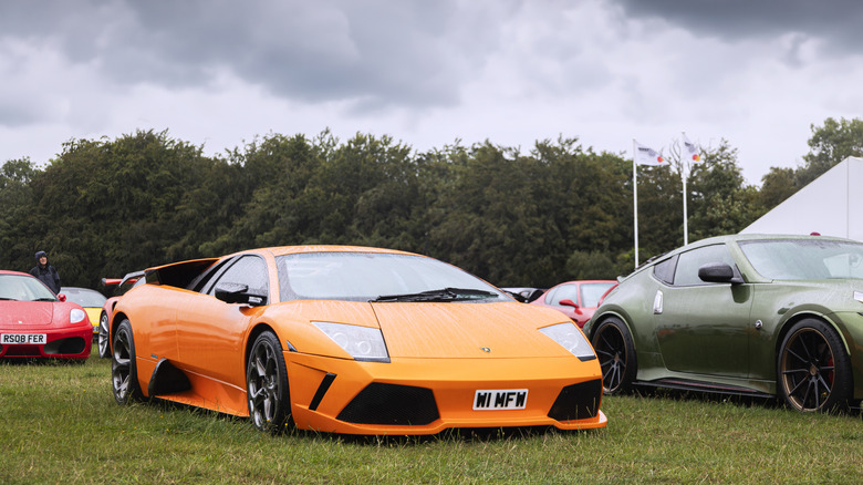 An orange Lamborghini Murcielago parked on the grass at a car show