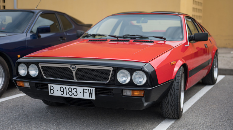 a red Lancia Montecarlo parked in a parking spot