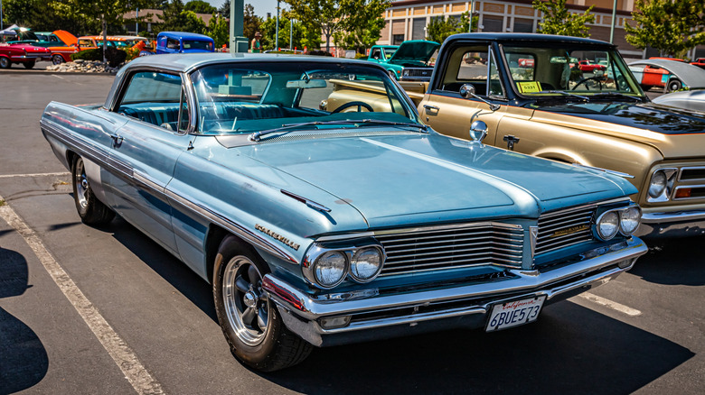a blue 1962 Pontiac Bonneville sitting in a parking lot during a classic car show