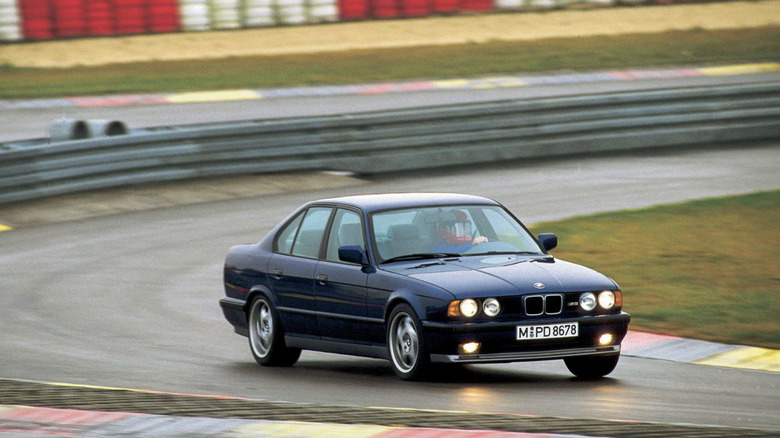 A 1995 BMW M5 driving down a raceway in the rain