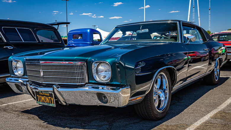 a chevy monte carlo parked in a parking lot during a classic car show on a sunny day