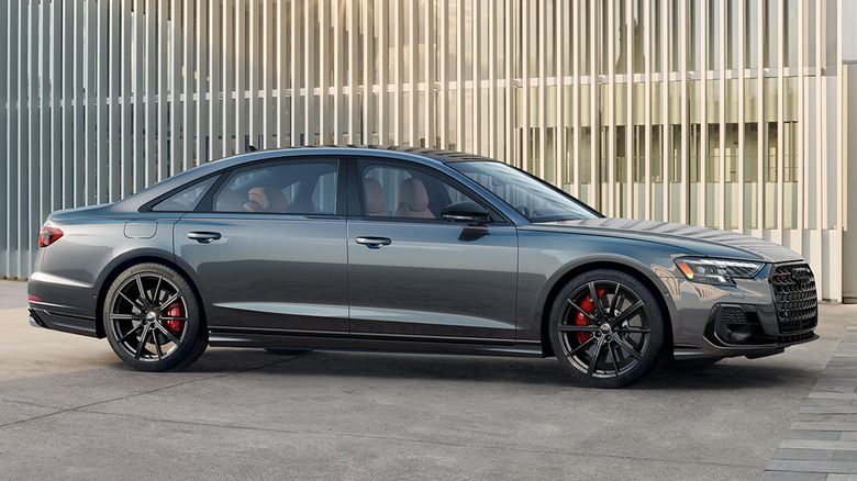 A side view of a gray Audi S8 parked in front of a slatted fence