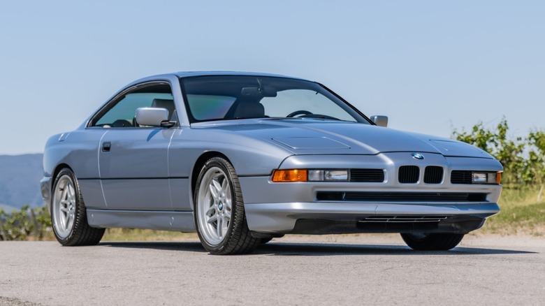 front three quarters shot of a silver 1991 BMW 850ci parked on asphalt in front of grass and a bleu sky