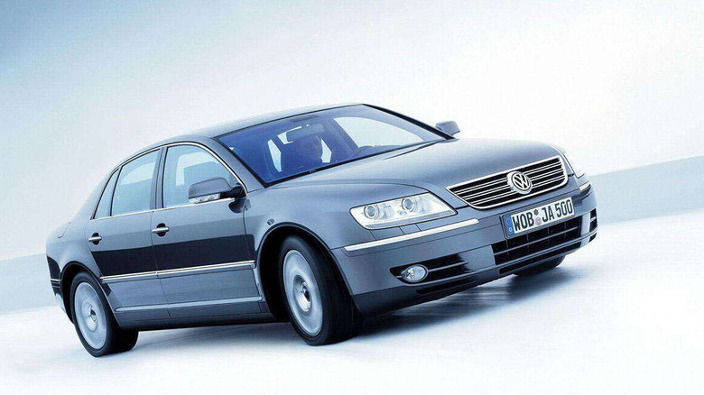 A front three quarters shot of a silver VW Phaeton driving in an all-white scene