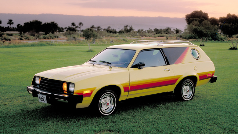 A ford pinto wagon parked on some grass at sunset