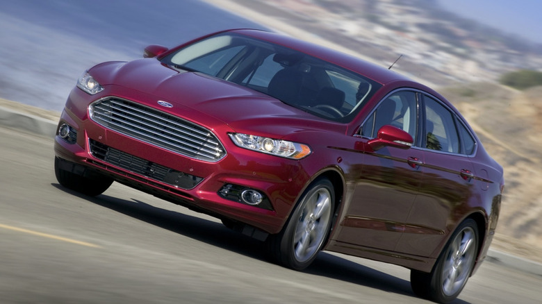 A red Ford Fusion driving down a road with a dutch angle.