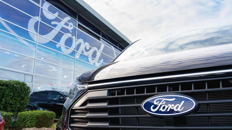 Ford offices front with the ford logo displayed on the glass. a ford car is in the foreground, it's badge visible