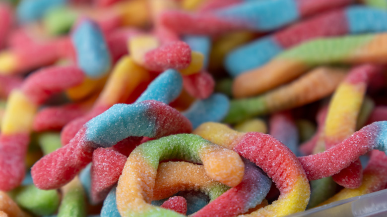 A shallow depth of field shot of multicolored gummy worms (blue, red, orange, green) piled together at a candy shop