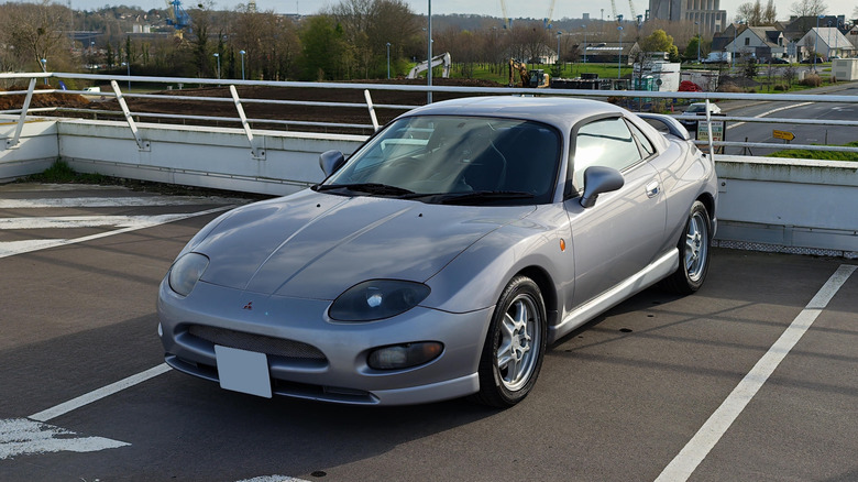 A silver 1995 Mitsubishi FTO from the front corner driver's side, parked on an empty parking structure.