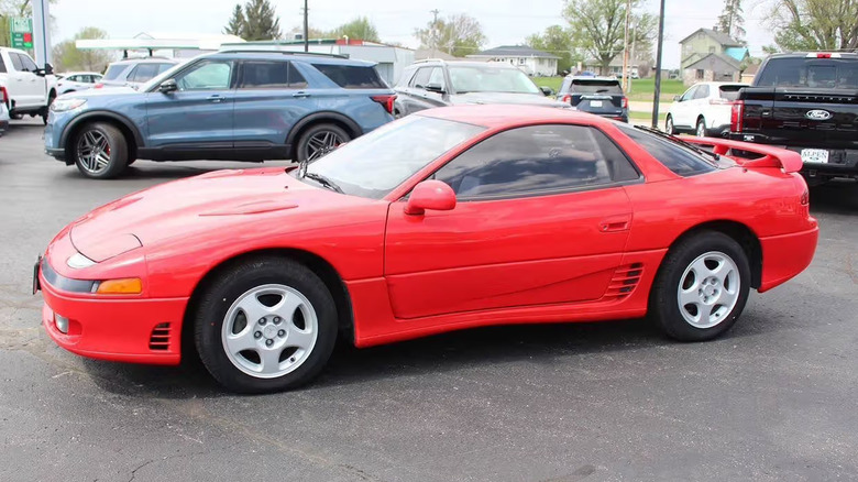 The driver's side of a red, 1991 Mitsubishi 3000GT in a dealer parking lot.