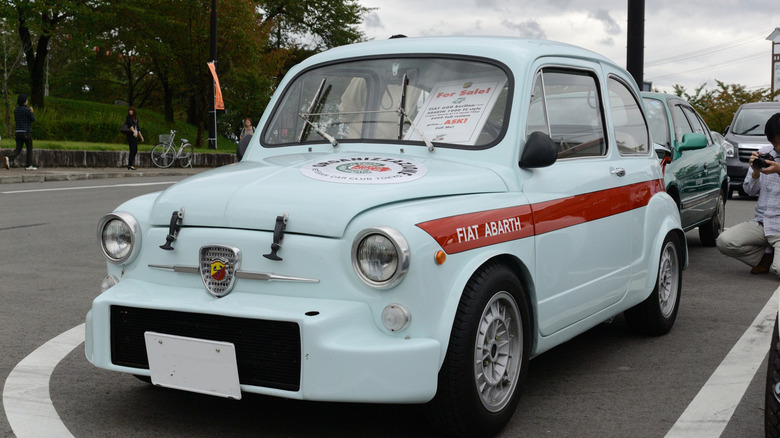 A fiat-abarth 600 parked on a british street with a "for sale" sign