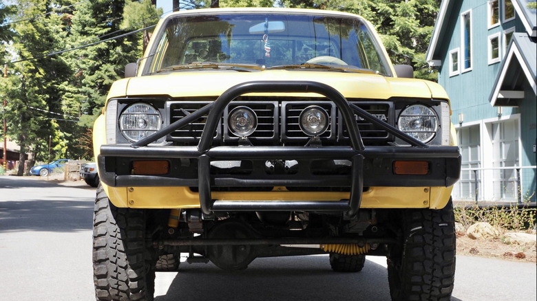 A yello 1980 Toyota 4x4 parked on a suburban street on a clear sunny day