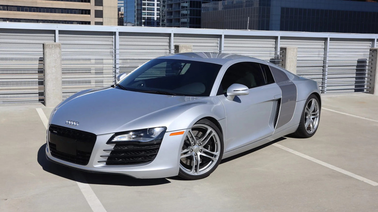 Front three-quarters shot of a silver Audi R8 parked in front of a wall