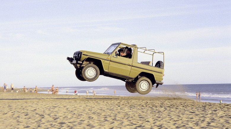 A green Mercedes-Benz G-Class jumping on the beach