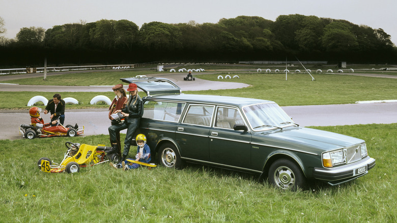 A green Volvo 265 wagon parked at a go-kart track