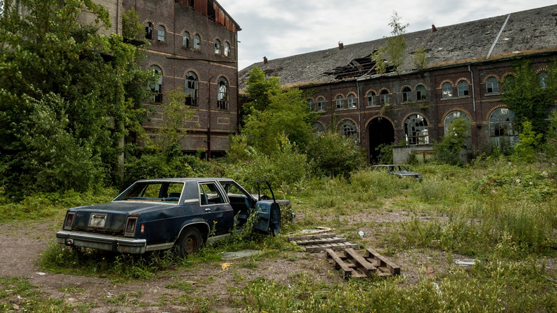 08-09-2010.Charleroi.Belgium.1980 Ford LTD wreck on an empty abandoned industrial site with damaged buildings